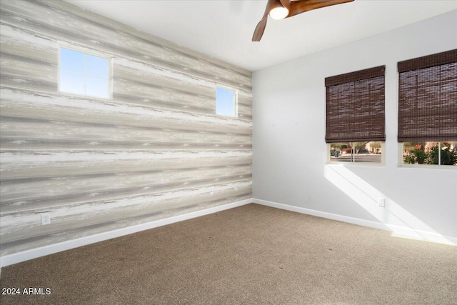 unfurnished room with carpet floors, ceiling fan, and wooden walls