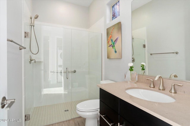 bathroom with an enclosed shower, vanity, toilet, and wood-type flooring