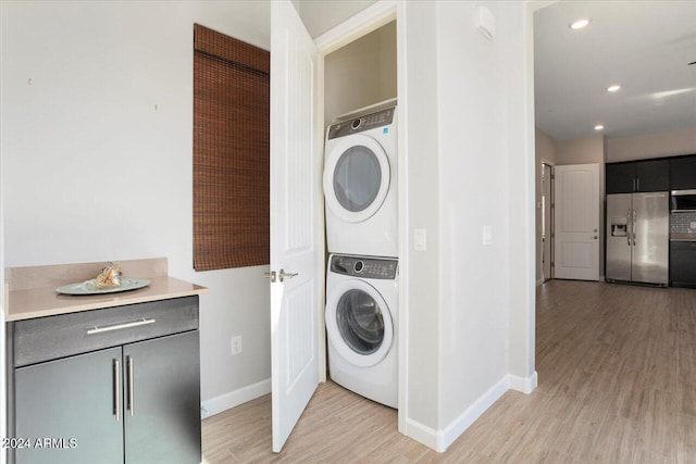 laundry room featuring stacked washing maching and dryer and light hardwood / wood-style floors