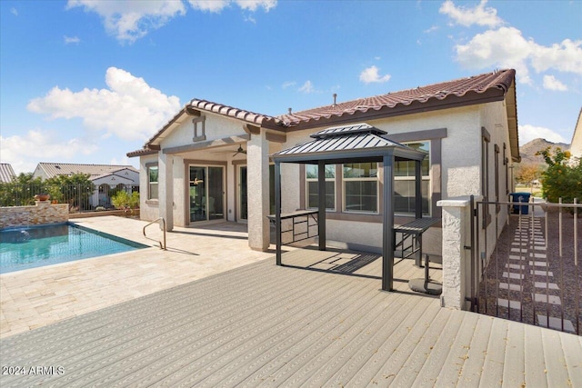 rear view of house featuring a gazebo and a swimming pool side deck