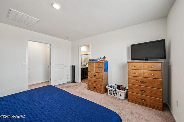 bedroom featuring light colored carpet and ensuite bath