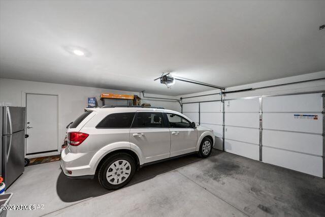 garage with a garage door opener and stainless steel refrigerator