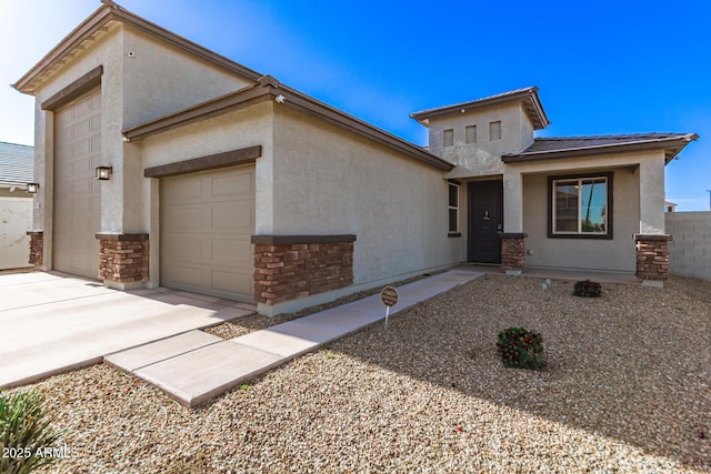 prairie-style house featuring a garage, stucco siding, concrete driveway, and stone siding