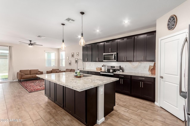 kitchen featuring a sink, backsplash, stainless steel appliances, and light wood finished floors