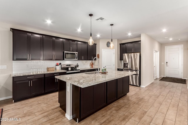 kitchen featuring visible vents, appliances with stainless steel finishes, tasteful backsplash, light wood-type flooring, and a sink