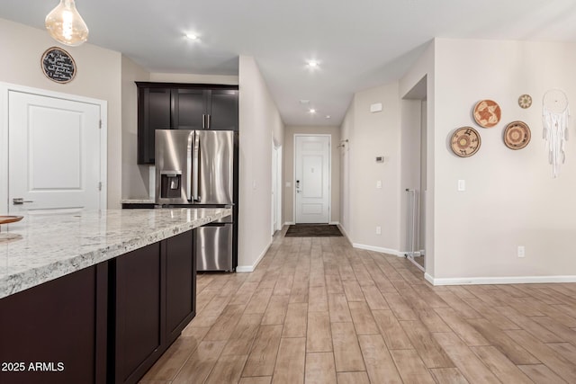 kitchen with light stone countertops, stainless steel fridge with ice dispenser, baseboards, recessed lighting, and light wood-style flooring
