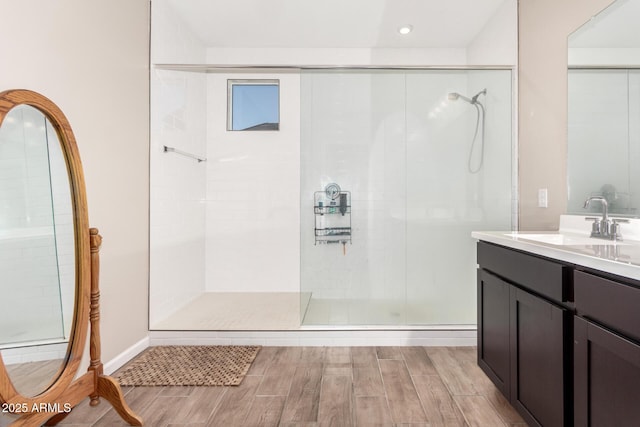 full bath with recessed lighting, a tile shower, wood finished floors, and vanity