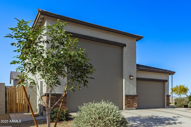 view of front of house with fence, an attached garage, driveway, and stucco siding