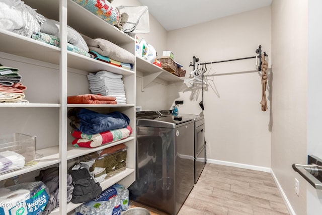 laundry area with baseboards, laundry area, washing machine and dryer, and light wood finished floors