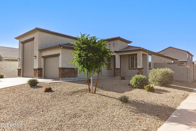 view of front of house with fence, an attached garage, stone siding, stucco siding, and concrete driveway