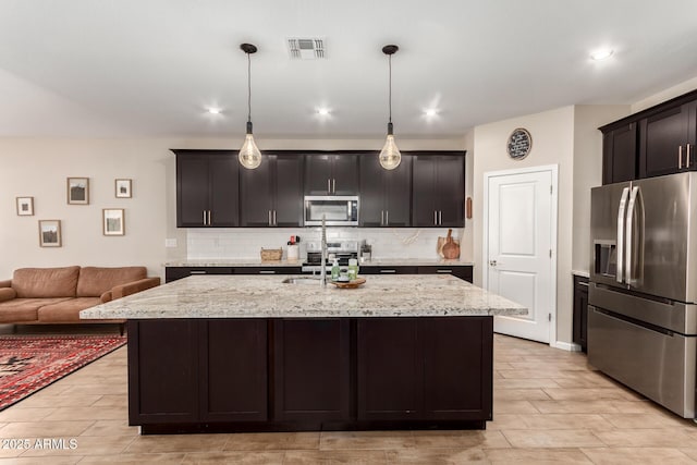 kitchen featuring wood tiled floor, decorative backsplash, visible vents, open floor plan, and stainless steel appliances