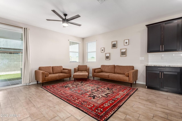 living area with baseboards, a ceiling fan, and light wood-style flooring