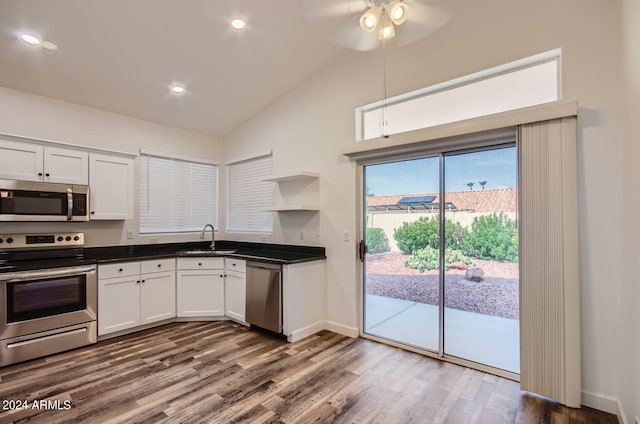 kitchen featuring sink, white cabinetry, vaulted ceiling, hardwood / wood-style flooring, and stainless steel appliances