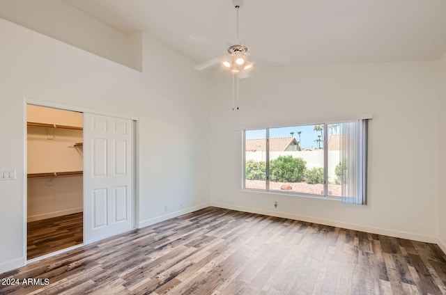 unfurnished bedroom featuring ceiling fan, high vaulted ceiling, hardwood / wood-style floors, and a closet