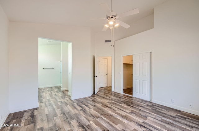 unfurnished bedroom featuring high vaulted ceiling, light hardwood / wood-style floors, a closet, and ceiling fan