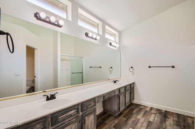 bathroom with wood-type flooring, toilet, an enclosed shower, and vanity