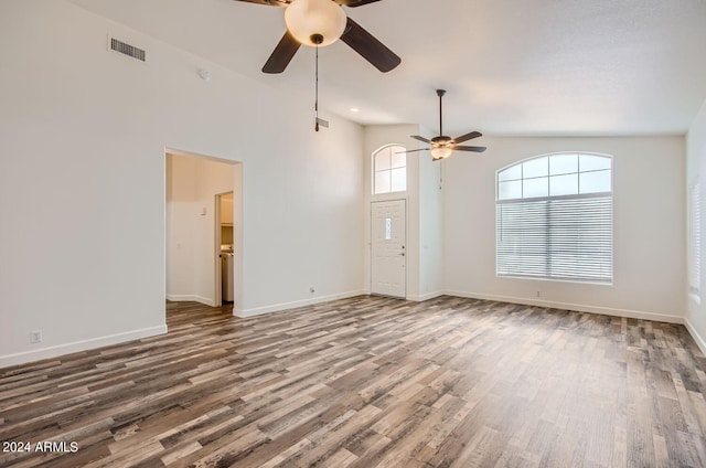 unfurnished living room featuring wood-type flooring, ceiling fan, and a high ceiling