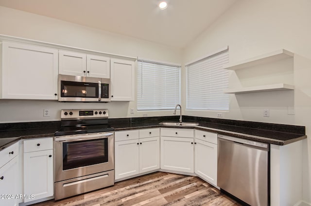 kitchen with stainless steel appliances, sink, white cabinets, and light wood-type flooring