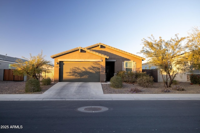 single story home featuring stucco siding, a tile roof, fence, concrete driveway, and an attached garage