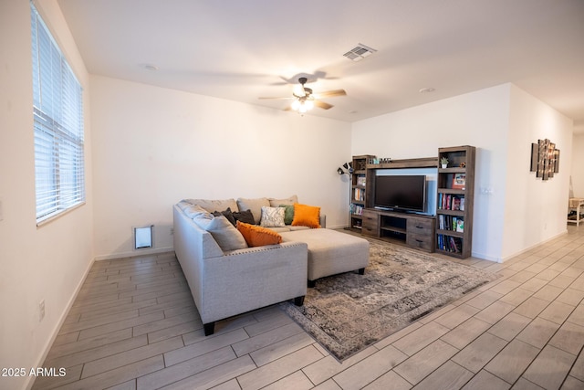 living room featuring wood finish floors, visible vents, baseboards, and a ceiling fan