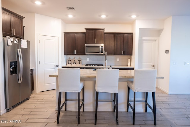 kitchen with dark brown cabinetry, appliances with stainless steel finishes, and wood tiled floor