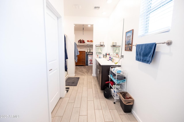 hallway with baseboards, visible vents, and wood finish floors