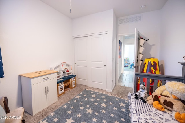 bedroom with visible vents, a closet, and light carpet