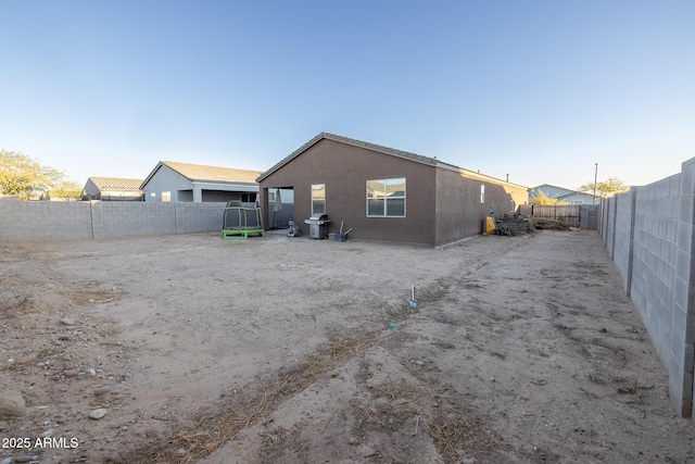 rear view of house featuring stucco siding and a fenced backyard