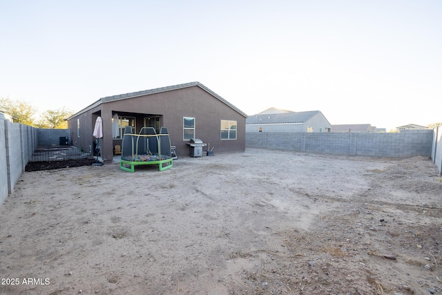 back of house featuring a trampoline and a fenced backyard