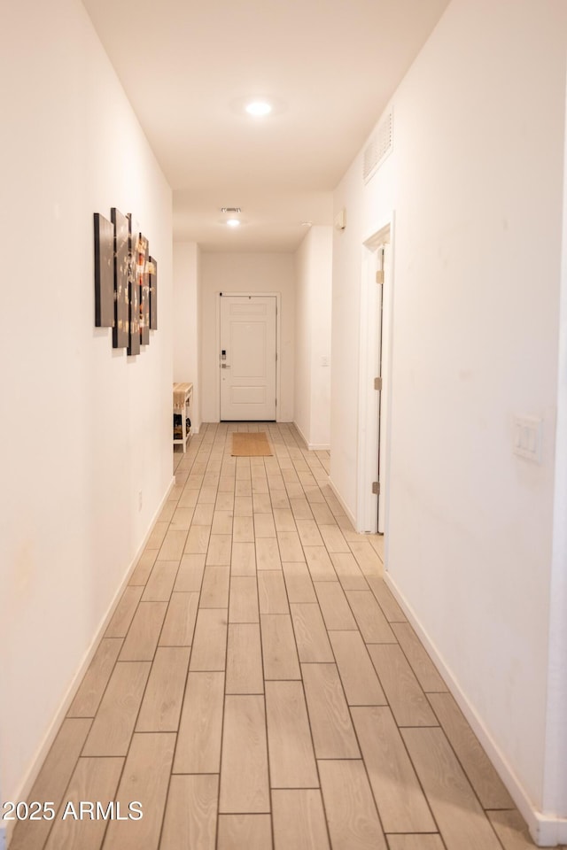 hall with visible vents, baseboards, and wood finish floors