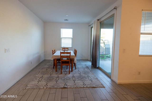 dining room with wood finished floors, visible vents, and baseboards