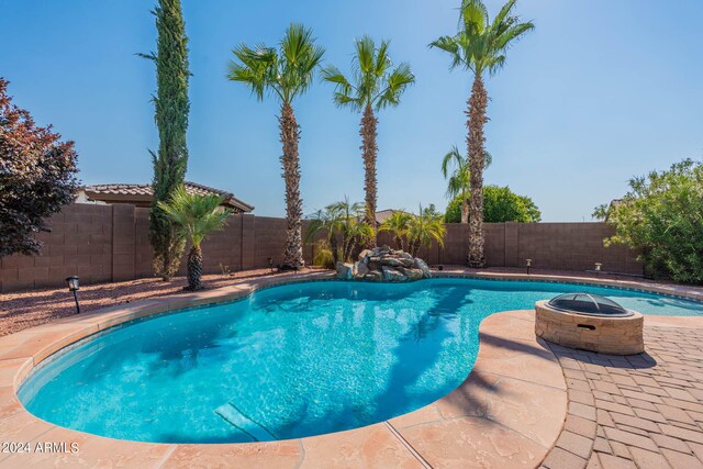 view of pool with an outdoor fire pit and a patio