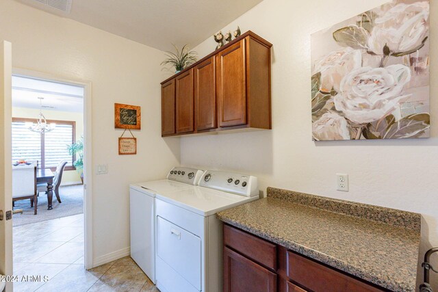 laundry area with a notable chandelier, cabinets, washing machine and dryer, and light tile patterned floors