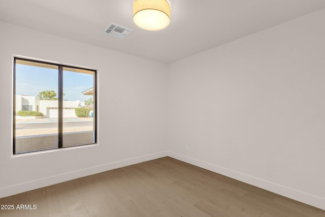 unfurnished room featuring visible vents, baseboards, and wood finished floors