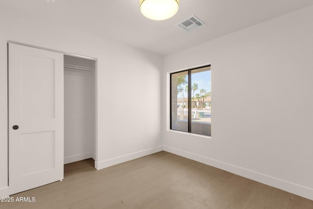 unfurnished bedroom with baseboards, a closet, visible vents, and light wood-style floors