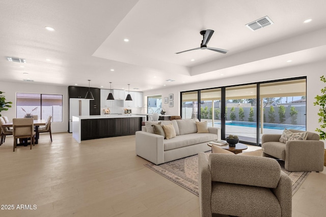 living room featuring light wood-style flooring, visible vents, and recessed lighting