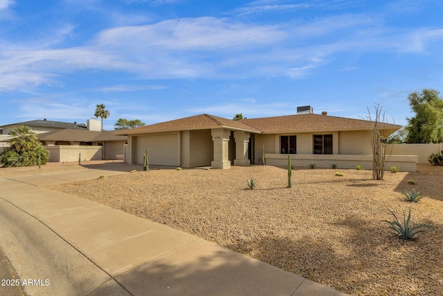 ranch-style house featuring a garage, driveway, and fence