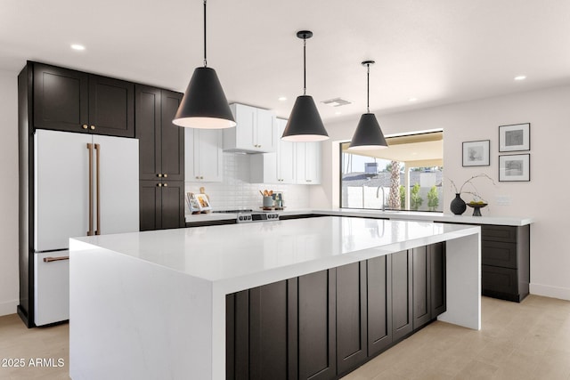 kitchen featuring decorative backsplash, range, a large island, freestanding refrigerator, and light countertops