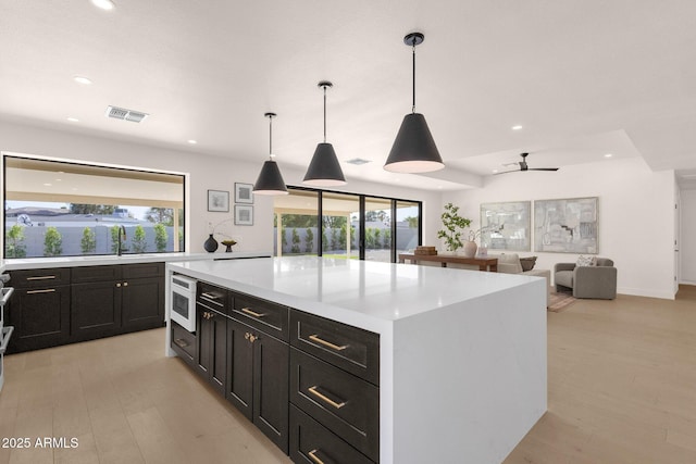 kitchen with recessed lighting, visible vents, light countertops, dark cabinetry, and a center island