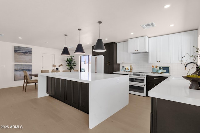 kitchen with a center island, high end appliances, light countertops, visible vents, and a sink