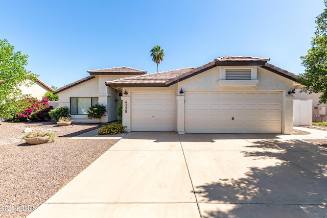 view of front of house with driveway, a garage, stucco siding, and a tiled roof