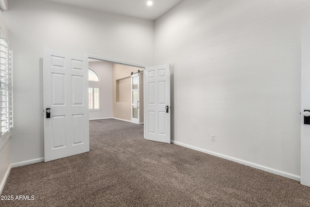 carpeted empty room featuring baseboards and a high ceiling