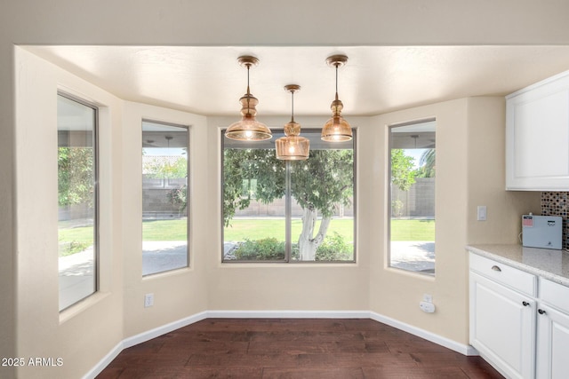 unfurnished dining area with dark wood-style floors and baseboards