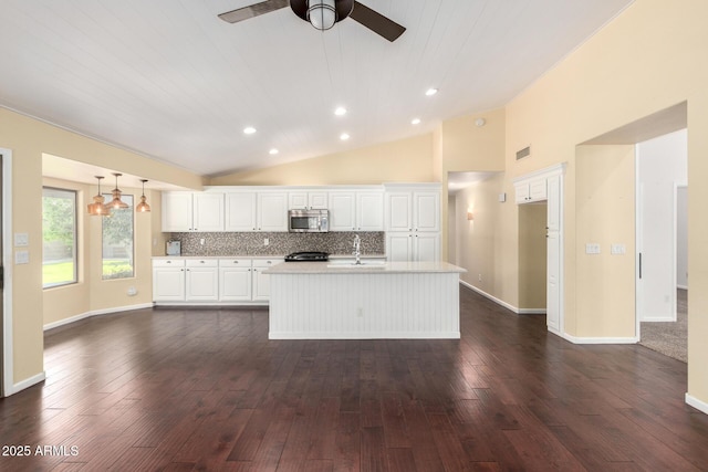 kitchen with stainless steel microwave, light countertops, a sink, white cabinetry, and ceiling fan