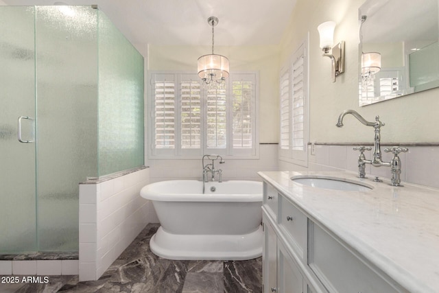 bathroom featuring a shower stall, a chandelier, a freestanding bath, vanity, and tile walls