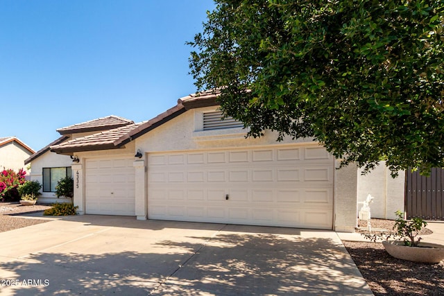 view of front of property with stucco siding, a tile roof, driveway, and an attached garage