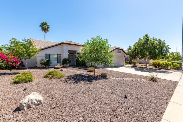 view of front facade with concrete driveway, stucco siding, a tile roof, and a garage