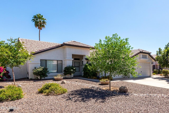 view of front of property featuring a tiled roof, an attached garage, driveway, and stucco siding