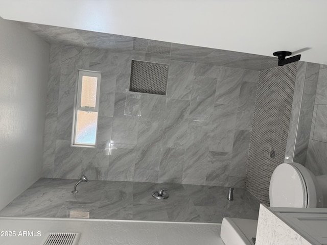 full bath with toilet and tiled shower