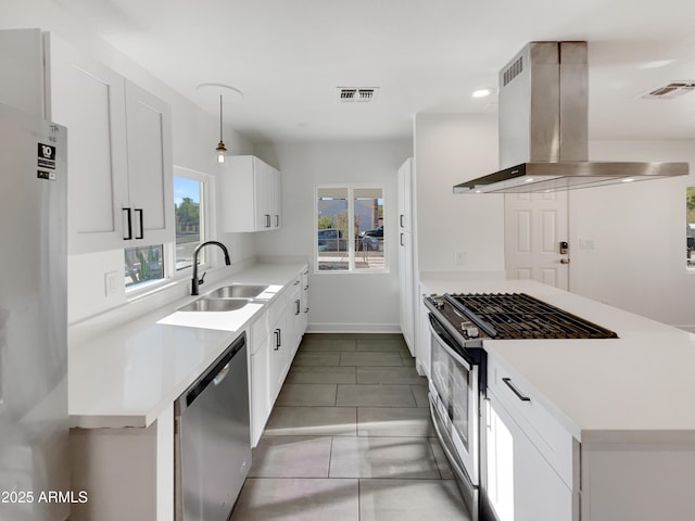 kitchen with wall chimney exhaust hood, stainless steel appliances, a healthy amount of sunlight, sink, and white cabinetry